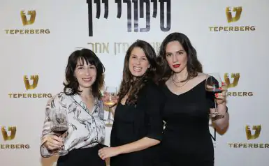 3 בנות מחייכות ומחזיקות גביע יין